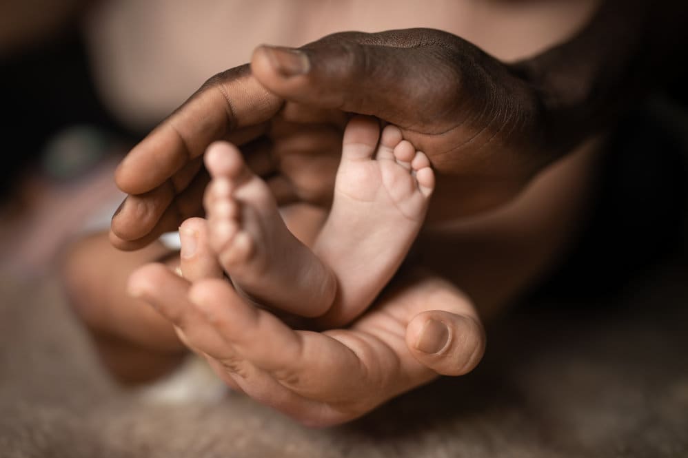 2 newborn feet being cupped by parents hands.