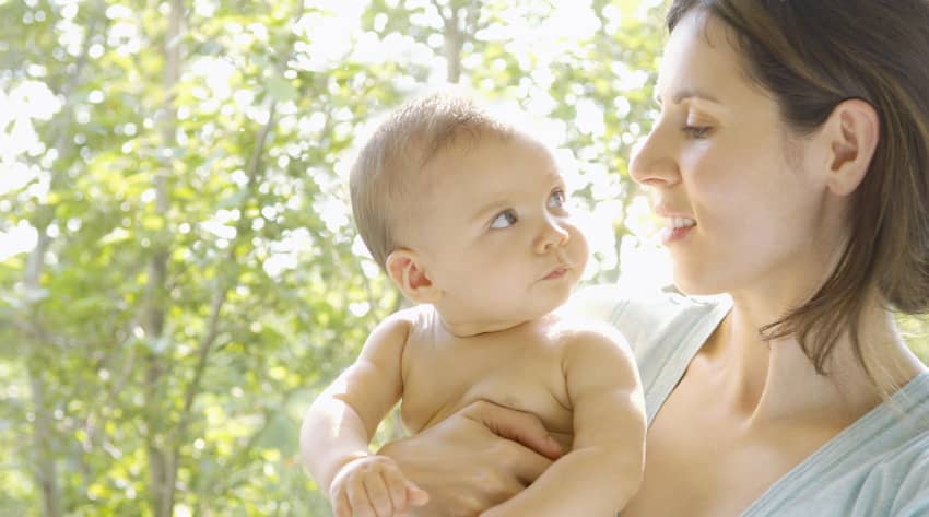 Mother holding and looking at a naked baby in the eyes Mother holding and looking at a naked baby in the eyes