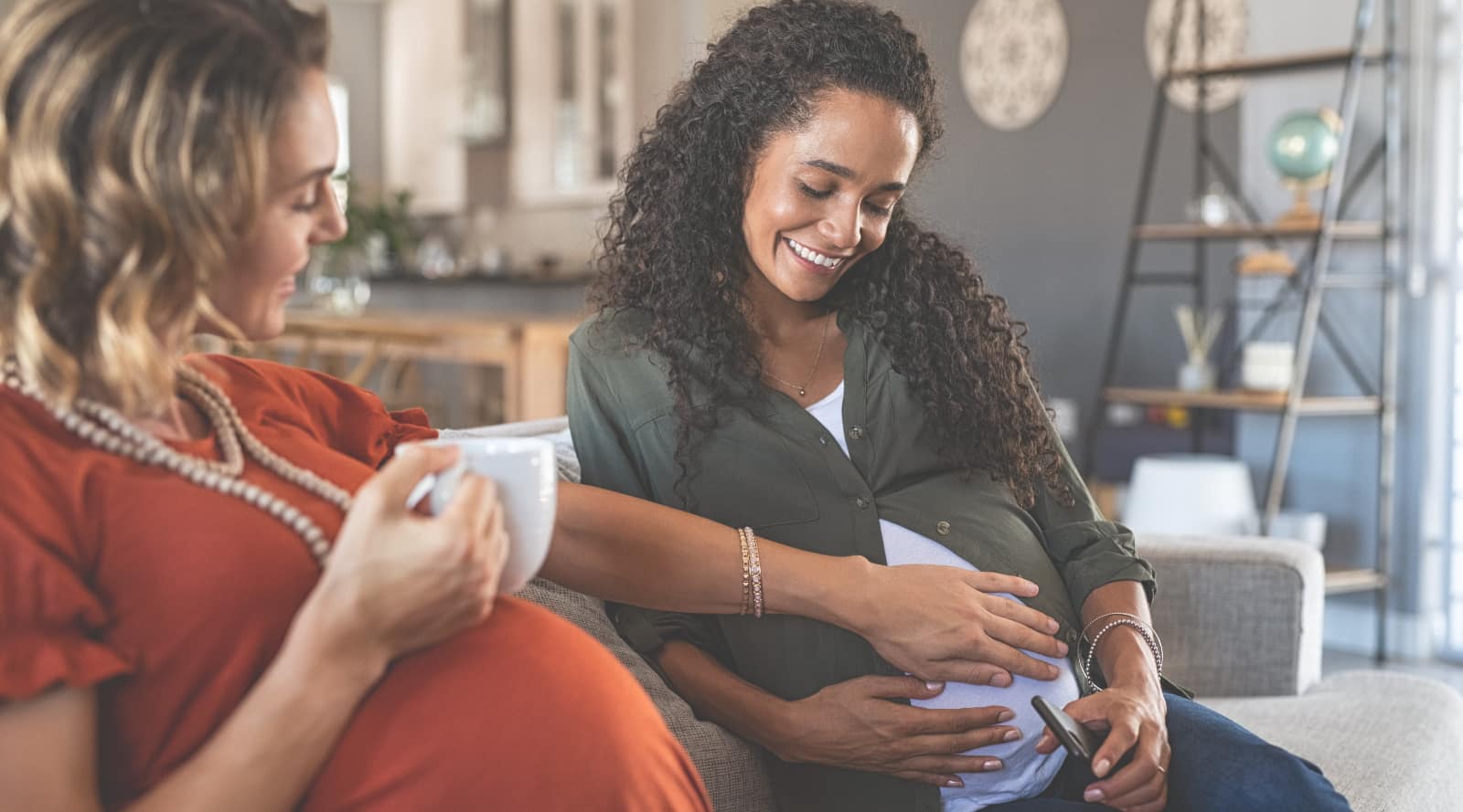 Two pregnant women socialising over a hot beverage.