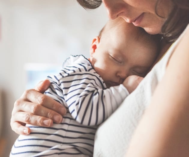 baby sleeping in mother’s arms