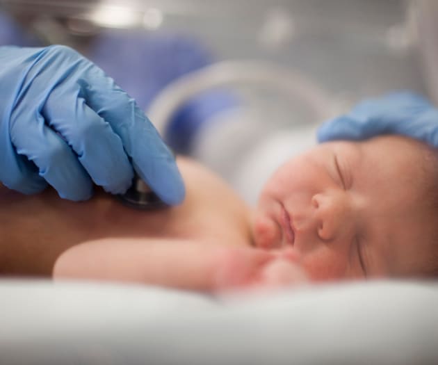 A doctor checking a premature baby’s heartbeat