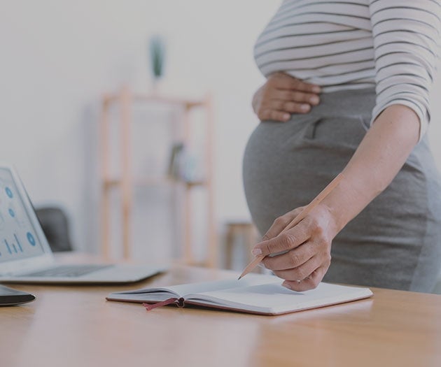 Pregnant mother working at the office and holding her bump