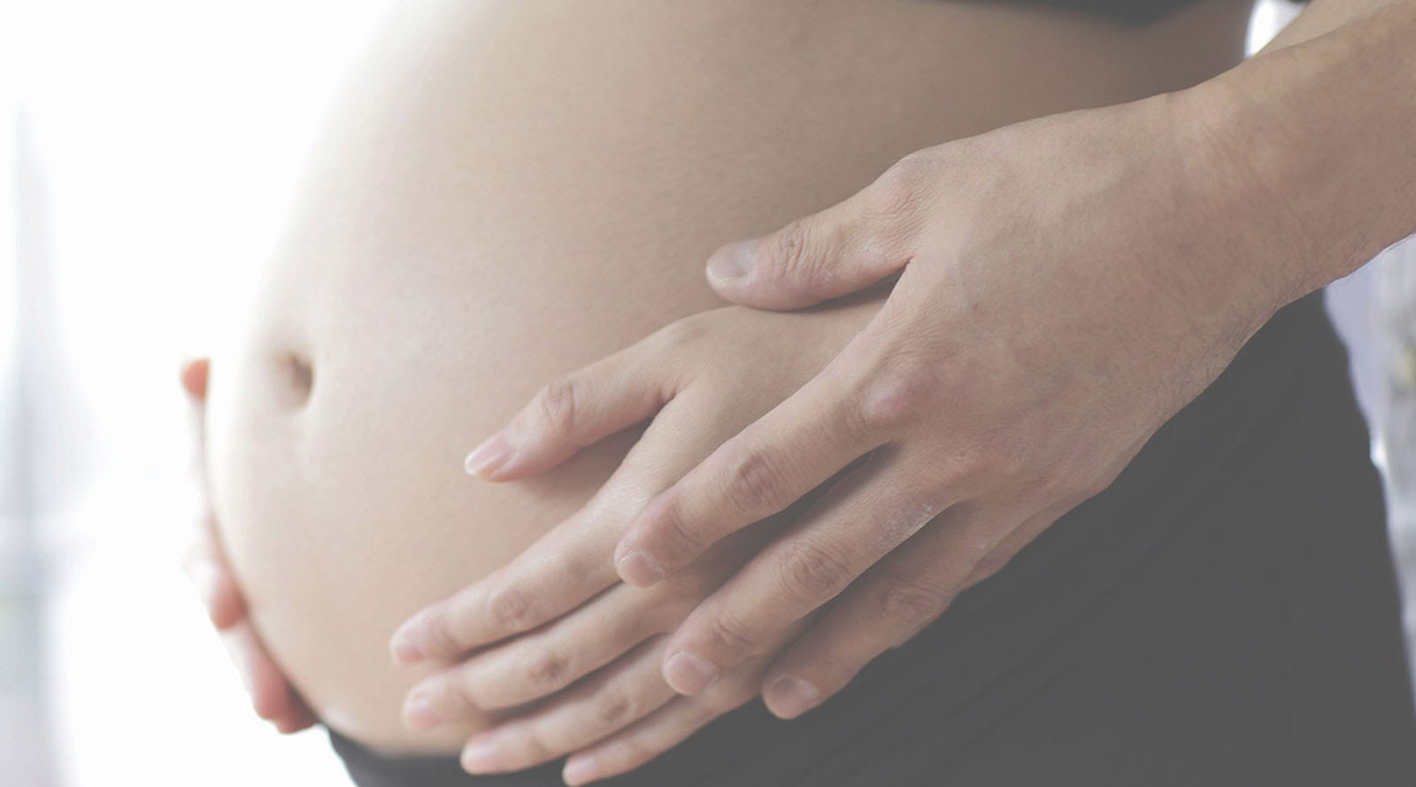 Mother and partner holding baby bump