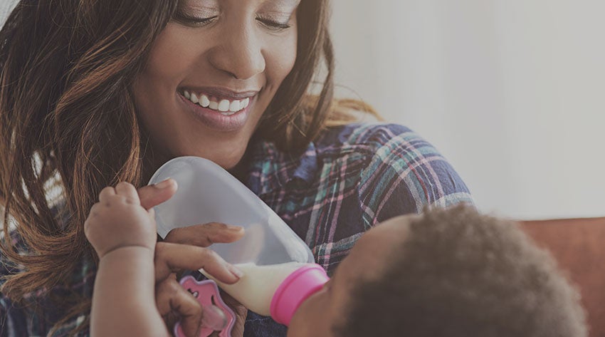 Mother feeding baby with bottle of expressed milk Mother feeding baby with bottle of expressed milk