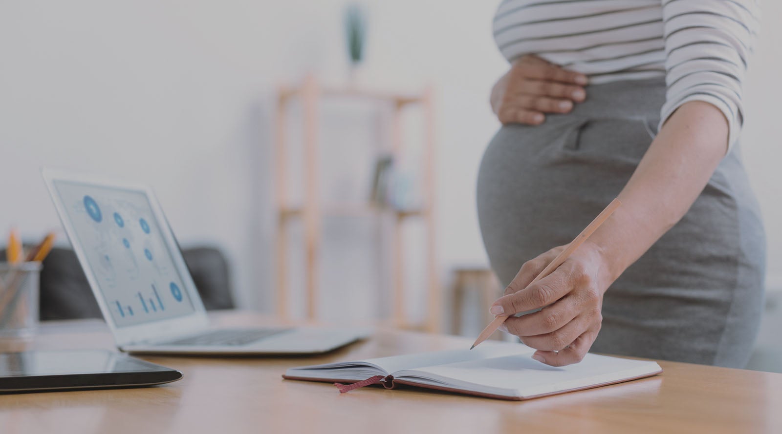 Pregnant mother working at the office and holding her bump