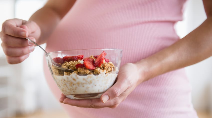 sma_pregnancydiet_body_3_850.jpg pregnant mother holding a bowl of yoghurt, granola and strawberries